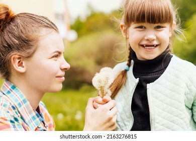 Happy sisters hold dandelions together in the park in the spring. Caring, loving older sister gives wildflowers to her younger cheerful sister. The concept of a Carefree childhood. Sisterly friendship - Shutterstock ID 2163276815