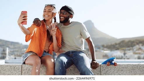 Happy, skateboard and couple taking a selfie on a phone while sitting on a rooftop in the city. Happiness, peace sign and young interracial man and woman taking photo with smartphone in a urban town. - Shutterstock ID 2264496971