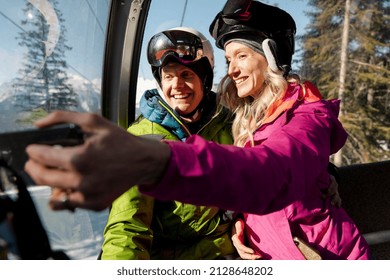Happy skier couple taking selfie in sunny ski lift gondola - Shutterstock ID 2128648202