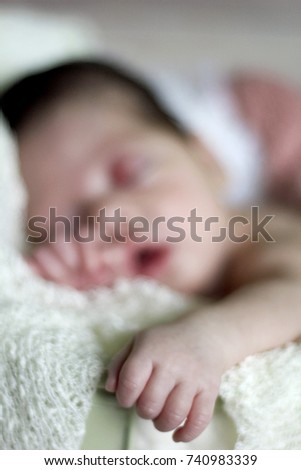 Newborn baby girl sleeping on blue sheets at home