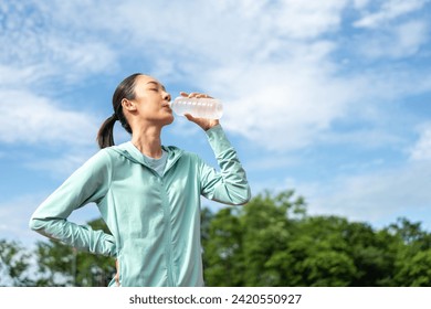 Happy slim asian woman drinking water after workout exercising on running track at sport stadium. Young beautiful asian drinking water after jogging running outdoor. Healthy and active lifestyle. - Powered by Shutterstock