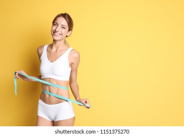 Happy slim woman in underwear with measuring tape on color background. Positive weight loss diet results