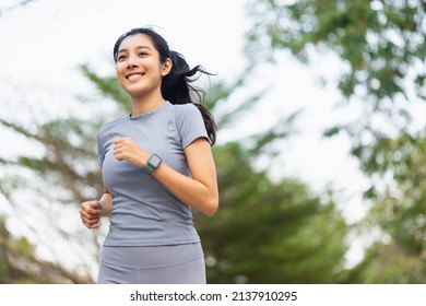Happy slim woman wearing sportswear jogging in the city at sunrise. Young beautiful asian female in sports bra running outdoor. Workout exercise in the morning. Healthy and active lifestyle concept. - Shutterstock ID 2137910295