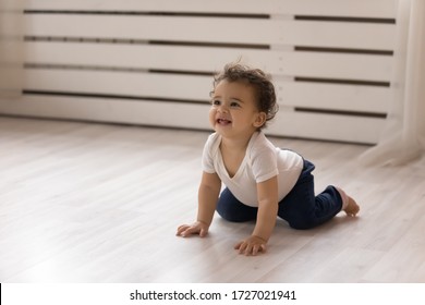 Happy Small Biracial Baby Girl Child Creep On All Fours On Warm Wooden Floor At Home, Smiling Cute Little African American Infant Toddler Go On Hands And Knees, Play Indoors, Childcare Concept