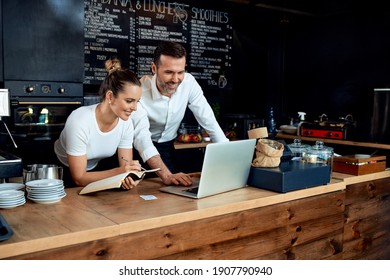 Happy Small Business Owners Working With Laptop At Cafe 