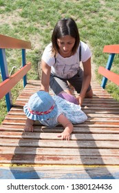 Happy Small Child And Mom On A Kids Playground. Little Girl In Dress Climbing On Jungle Gym And Mother Helping. Toddler Playing With Mother Outdoors On Sunny Summer Day. Woman Lifting Up Kid On Ladder