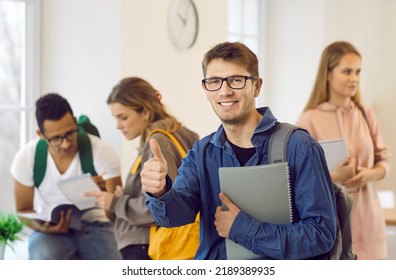 Happy Smart College Or University Student Achieves Success In Studies. Man Shows Thumbs Up, Content With Campus Life, Modern Academic Course Materials, Excellent Grades And Choice Of Degree And