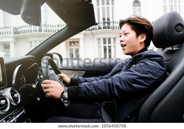 Happy Smart Driver on Luxury Convertible Car in\
Town with Sunlight