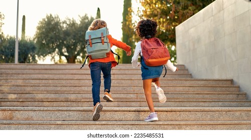 Happy smart kids with school bags rush to the lessons to school running up the stairs. Back to school. An African-American schoolgirl and her classmate walk down the street after school. - Powered by Shutterstock