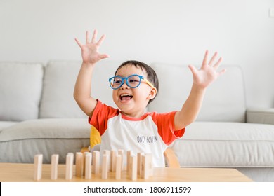 Happy Smart And Nerd Toddler Asian Boy Raised Hand When He Win Play Wooden Toy Block At Home.Boy Child Kid Wearing Glasses.myopia Or Short Sighted.Positive Human Emotion, Attitude And Self Esteem. 