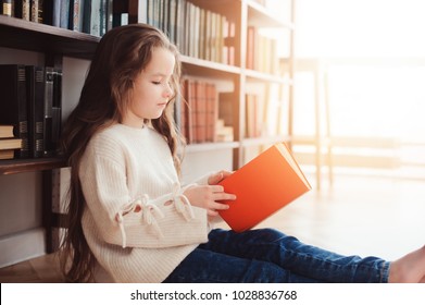 Happy Smart Schoolgirl Reading Books In Library Or At Home. Kids Early Learning And Education Concept.