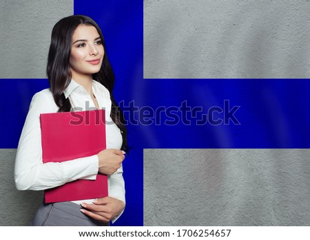 Happy smart woman with red book on Finnish flag background. Education or business concept