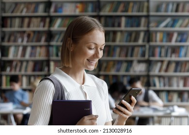 Happy smart Z gen millennial female student holding folder with study paper in hands, involved in using mobile software application, reading message communicating in social network, tech addiction. - Shutterstock ID 2130028916
