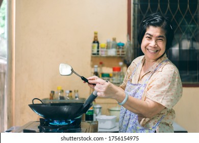 Happy Smile Asian Elderly Woman. Cooking With Love For Family Dinner Food Concept. Local Traditional Thai Style Outside Kitchen At Home. 