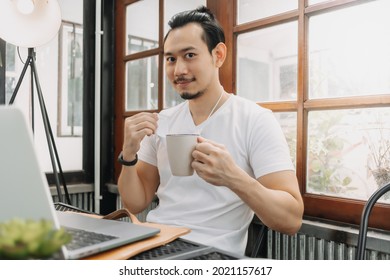 Happy And Smile Face Of Asian Man Drink Coffee While Working And Wearing Mask.