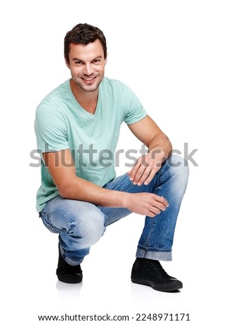 Happy, smile and portrait of a man in a studio with a casual, stylish and cool trendy outfit. Handsome, young and male model with natural fashion clothes crouching while isolated by white background.