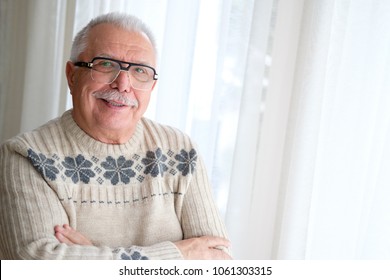 Happy And Smile Senior Man In Glasses 70-75 Years Old, Standing By Window With Armcross 