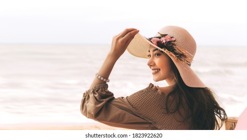 Happy Smile Young Adult Asian Woman Relax At Beach On Day. Wearing Dress Cloth And Sun Hat. Holidays Domestic Travel For Wellness Lifestyle Concept. Background With Copy Space.