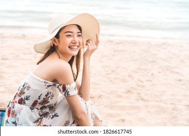 Happy Smile Young Adult Asian Woman Relax At Beach On Day. Wearing Dress Cloth And Sun Hat. Holidays Domestic Travel For Wellness Lifestyle Concept. Background With Copy Space.