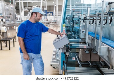 Happy smiled worker doing his job on Robotic factory line for processing and quality control in water factory.