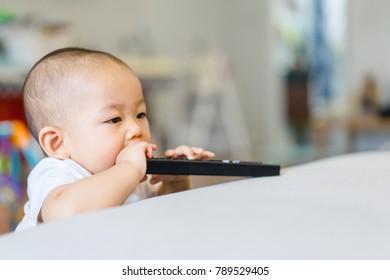 Happy smiling 10 month baby boy holding a remote control tv.child development concept. - Powered by Shutterstock