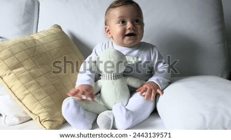 Happy smiling adorable beautiful baby boy seated on sofa home couch