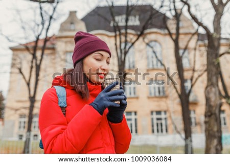 Happy smiling adult tourist woman holding paper coffee cup at the city street