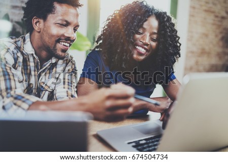 Happy smiling african american couple working together at home.Young black man and his girlfriend using laptop at home in the living room. Horizontal,blurred background.Flare