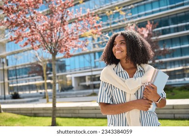 Happy smiling African American girl student standing in university park looking away outdoor dreaming of applying foreign university, study abroad, thinking of admission and scholarship, copy space. - Powered by Shutterstock
