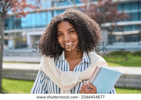 Happy smiling African American girl student standing outside university looking at camera outdoors, portrait. Applying foreign university, study abroad, admission and scholarship program concept.