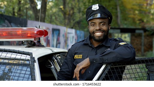Happy and smiling African American police officer looking at camera