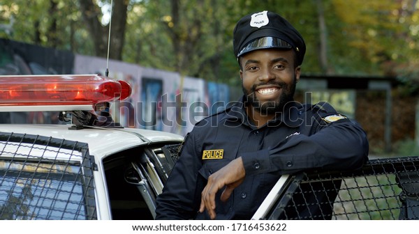 Happy and smiling African American police officer\
looking at camera
