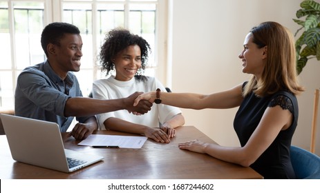 Happy Smiling African Married Couple Shake Hands To Mortgage Insurance Woman Broker. Formal Meeting With Financial Advisor, Real Estate Agent, Consulting, Make Deal, Handshake Gesture Of Trust Concept