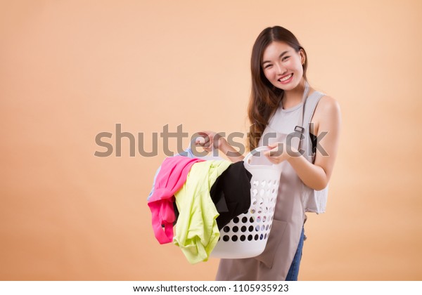 洗濯物のかごを持つ幸せな笑顔のアジア人女性 女の子の家政婦 女の子の家政婦 主婦 女の子の女の子のポートレートが洗濯物のかごを持っている アジアの若い成人女性モデル の写真素材 今すぐ編集