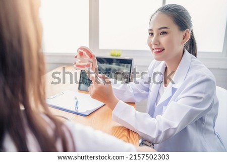 Happy smiling Asian dentist doctor examining teeth model diagnosing showing patient dental hygiene care tablet x-ray technology, healthcare expert orthodontist specialist hospital meeting office 