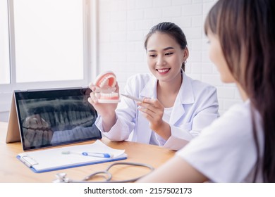 Happy Smiling Asian Female Dentist Doctor Examining Teeth Model Diagnosing Patient Dental Hygiene Using Tablet X-ray Technology, Healthcare Expert Orthodontist Specialist Hospital Meeting Office Room 