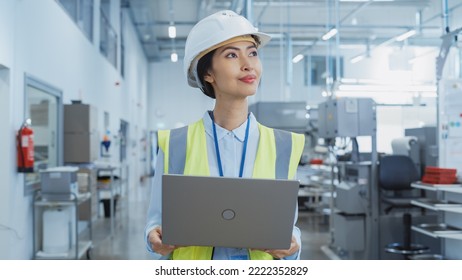 A Happy And Smiling Asian Female Engineer In White Hard Hat Standing With Laptop Computer At Electronic Manufacturing Factory. Successful Employee Watching The Work Flow