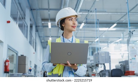 A Happy and Smiling Asian Female Engineer in White Hard Hat Standing with Laptop Computer at Electronic Manufacturing Factory. Successful Employee Watching the Work Flow - Powered by Shutterstock