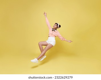 Happy smiling asian girl relaxing floating in mid-air isolated on yellow background.