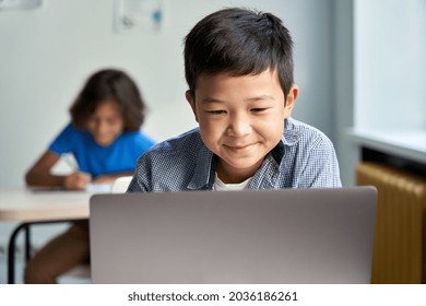 Happy Smiling Asian School Boy Using Laptop Computer At Class In Classroom. Smiling Chinese Junior School Student Learning Online Virtual Education Digital Program App Technology During Tech Lesson.