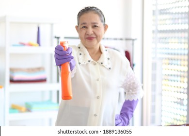 Happy Smiling Asian Senior Elderly Woman Housewife Wearing Rubber Gloves And Holding Cleaning Spray For Cleaning Up House, Grandma Doing Housework.