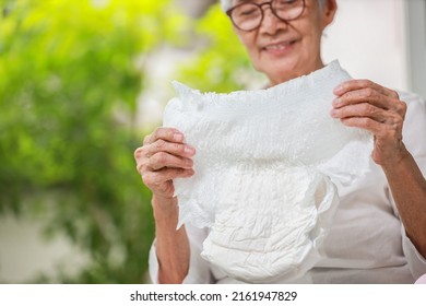 Happy Smiling Asian Senior Woman Showing Disposable Diaper For Adult,looking At Nappy Pamper With Satisfaction,old Elderly Patient With Urinary Incontinence,consumer Goods,health Care Concept