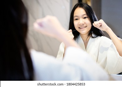 Happy Smiling Asian Teenager Girl Flossing Her Teeth,clean Her Healthy Teeth In Front Of A Mirror,people Brushing With Dental Floss In The Bathroom,Concept Of Teeth Care,oral Hygiene,dental Health