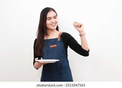 Happy smiling asian woman in apron holding empty plate showing gourmet sign over white background. cooking, culinary and people concept - Powered by Shutterstock