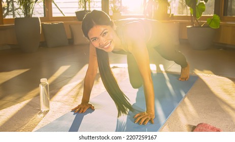 Happy And Smiling Asian Woman At Mountain Climber Exercise For Gaining Endurance. Young Female Person Strengthening Her Upper And Lower Body. Sporty Lady During Training Workout In Nice Golden Light.