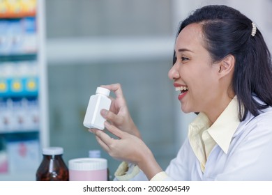 Happy Smiling Asian Women Pharmacist Showing Medicine Bottle On Her Hand In The Pharmacy Helth Care And Medicine Concept 