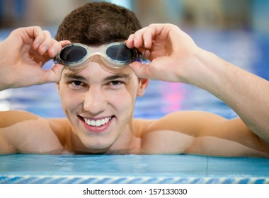 Happy smiling athletic swimmer wearing glasses at swimmingpool