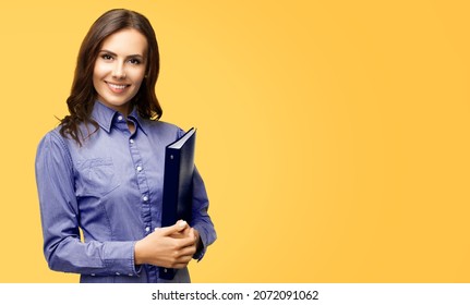 Happy Smiling Attractive Confident Businesswoman Holding Black Folder. Portrait Image - Young Brunette Corporate Business Lady Woman Employee Executive At Studio, Isolated Over Yellow Color Background