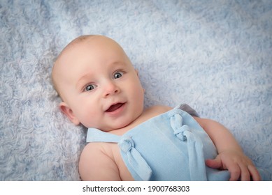 Happy And Smiling Baby In Blue Clothes On Blue Color Background