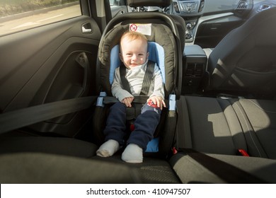 Happy Smiling Baby Boy Posing In Child Safety Car Seat